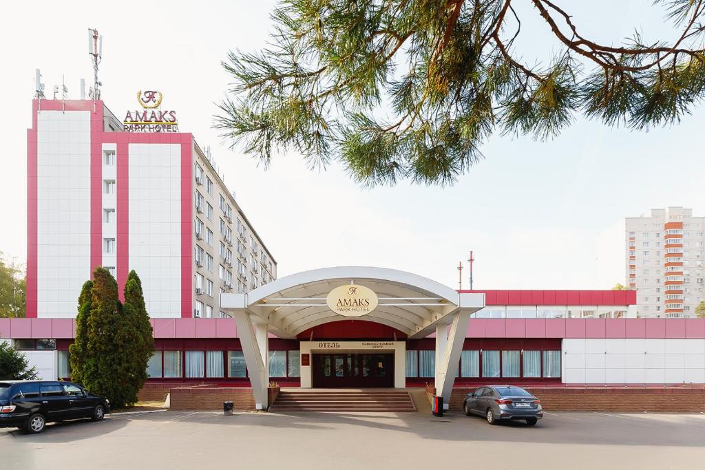 a hotel with cars parked in a parking lot at AMAKS Park Hotel in Voronezh