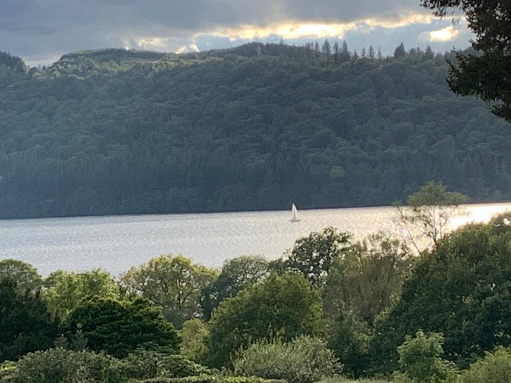 a sail boat on a lake with a mountain at The Lady of the Lake Windermere in Windermere