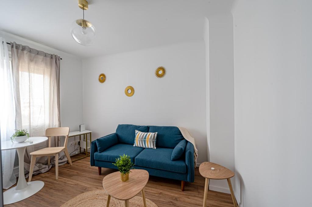 een woonkamer met een blauwe bank en een tafel bij Le Petit Drancy - T2 tout équipé in Drancy