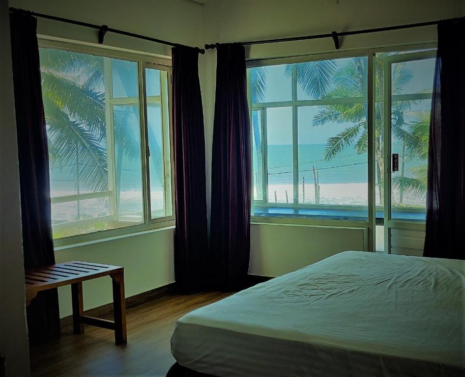 a bedroom with a bed and a view of the beach at White Shell Beach House in Kannur