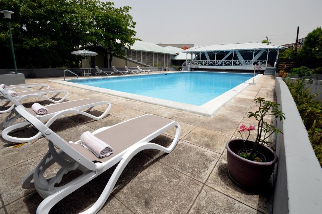 a swimming pool with lounge chairs next to at The Liguanea Club in Kingston