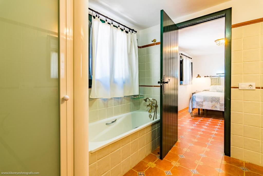 a bathroom with a bath tub and a bedroom at Cortijo El Indiviso in Vejer de la Frontera