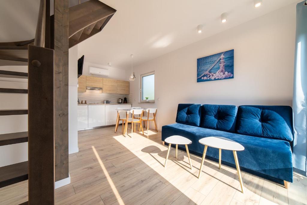 a living room with a blue couch and a kitchen at Marina Domki Apartamentowe in Jastarnia