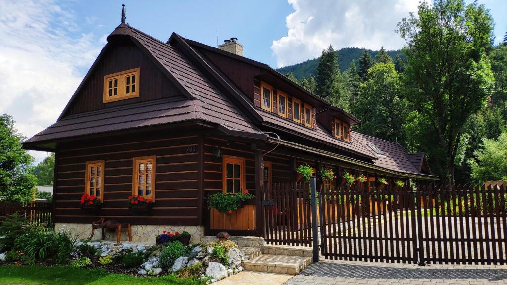 a small wooden house with a black fence at Chalupa Skokanovo Slovenský raj in Hrabušice