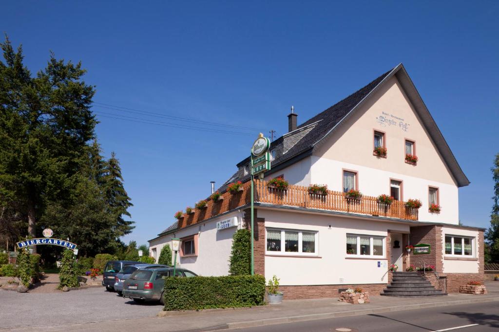 Hotel-Restaurant Birgeler Hof في Birgel: مبنى ابيض كبير فيه سيارات تقف امامه