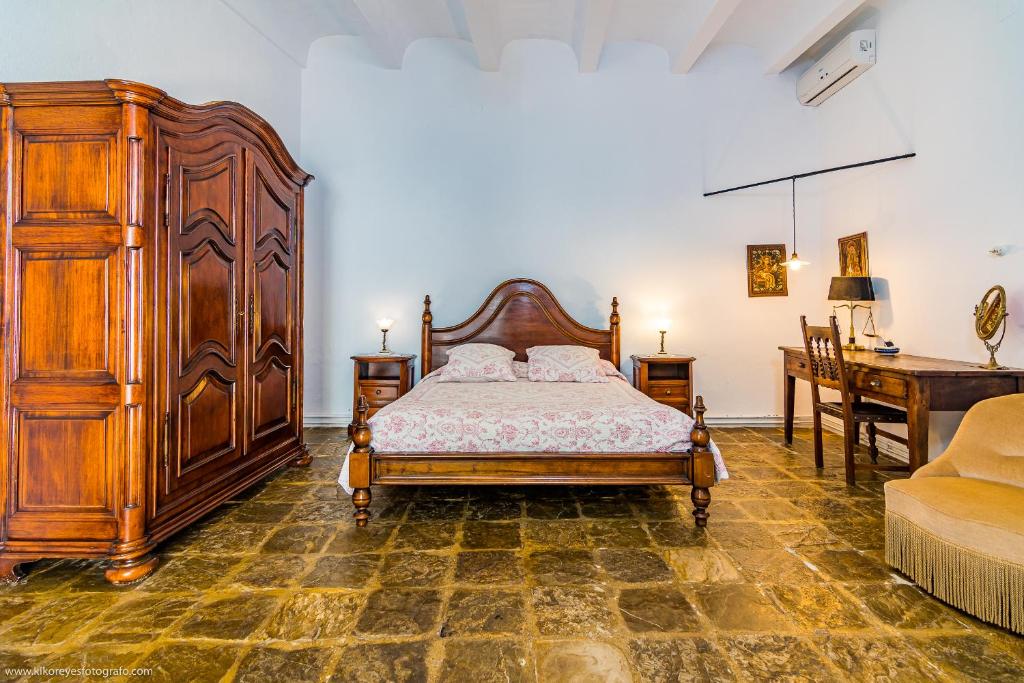 a bedroom with a large wooden bed and a desk at Cortijo El Indiviso in Vejer de la Frontera