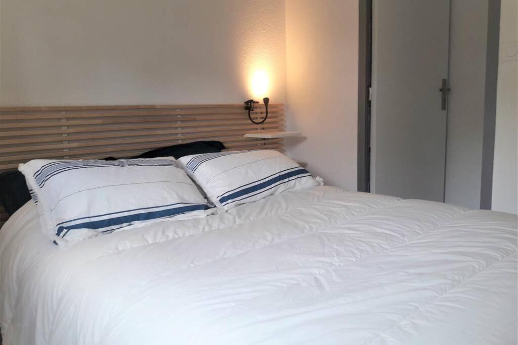 un lit blanc avec des oreillers bleus et blancs dessus dans l'établissement Maison tout confort à la mer 200m de la plage, 2 chambres, 2min Royan, à Saint-Georges-de-Didonne