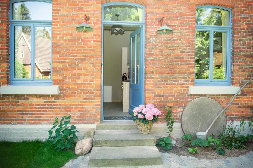 una casa de ladrillo con una puerta azul y una cesta de flores en Heuerhaus 1898 en Menslage