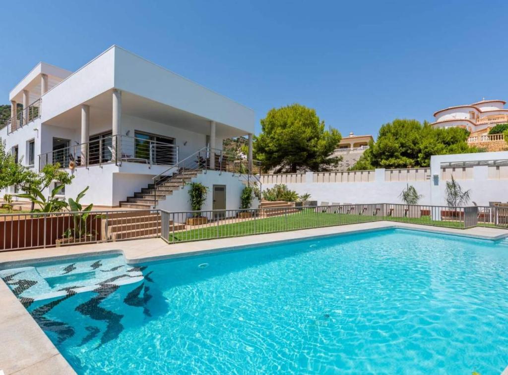 a villa with a swimming pool in front of a house at Villa Drago - Plusholidays in Calpe