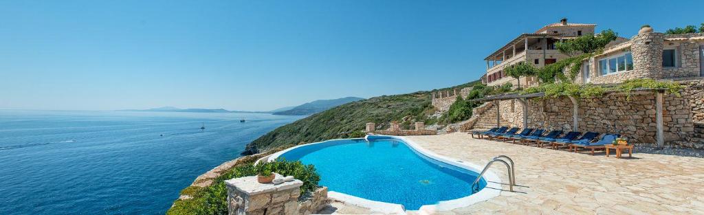 a swimming pool on a cliff next to the water at Luxury Zakynthos Villa Harron Villa 4 Bed Private Pool Agios Nikolaos in Zakynthos