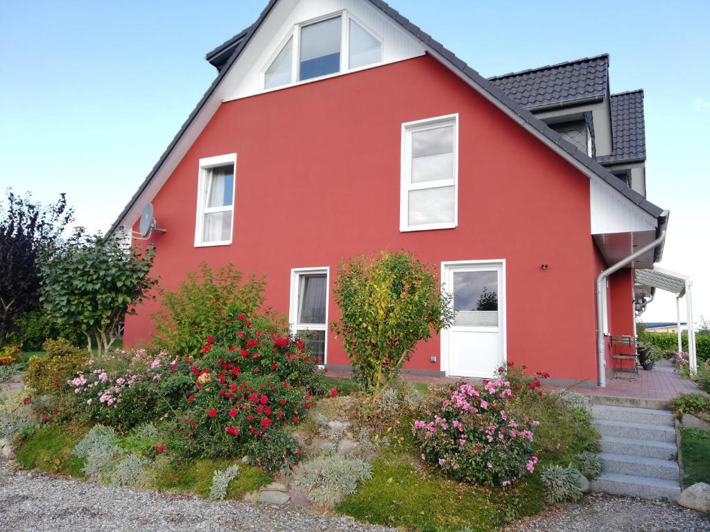 ein rotes Haus mit Blumen davor in der Unterkunft Ferienwohnung Nina Lütjenburg Klamp Ostsee in Lütjenburg