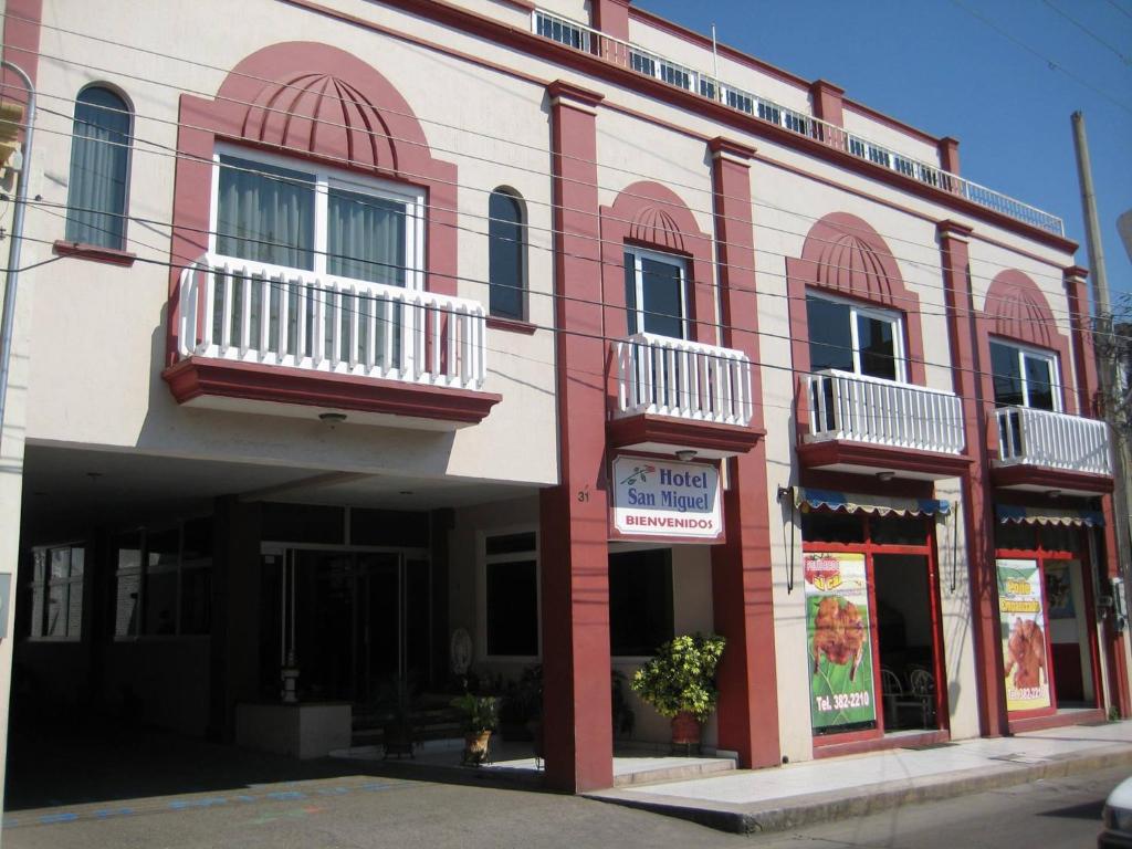 a red and white building with windows and balconies at Hotel San Miguel in Autlán de Navarro