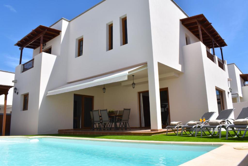 a villa with a swimming pool in front of a house at CASA BOUTIQUE LANZAROTE in Costa Teguise