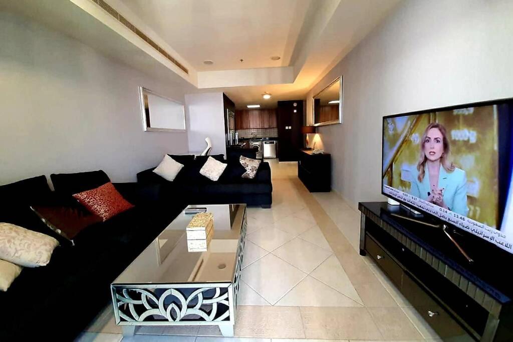 salon z czarną kanapą i telewizorem z płaskim ekranem w obiekcie skynest holiday homes princess tower 68th floor 1 bedroom apartment w Dubaju