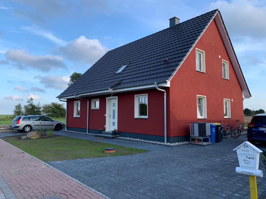 a red house with a car parked in front of it at Zur Vogelwiese in Bresewitz