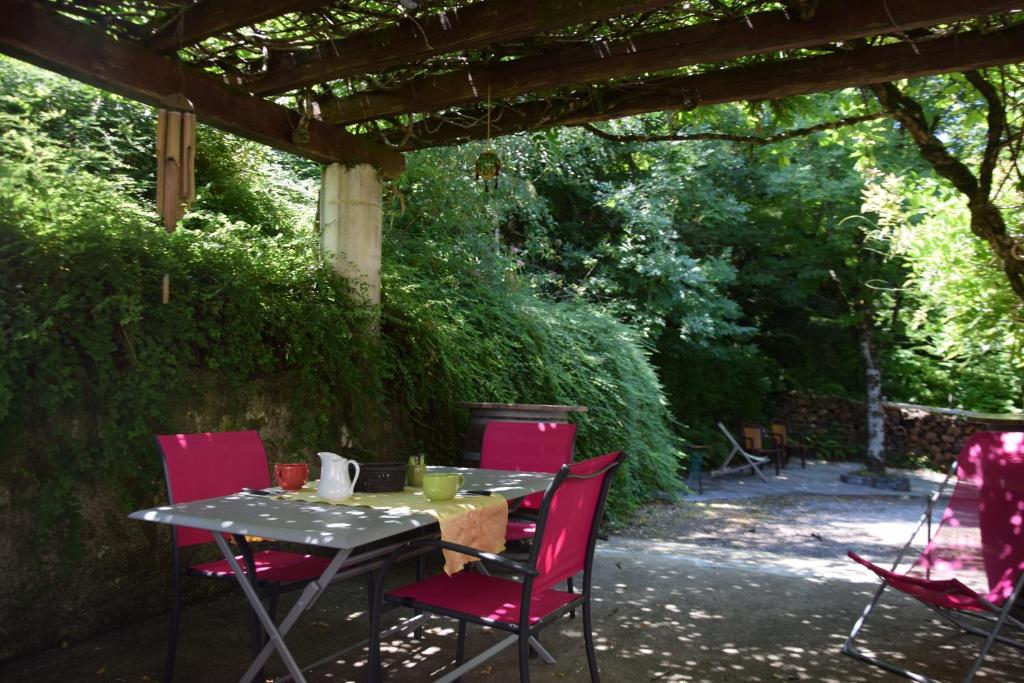 einen Tisch und Stühle unter einer Pergola in der Unterkunft Chambres d'Hôtes L'Orée des Bois in Lacrouzette