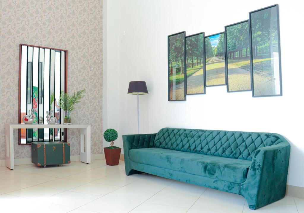 eine blaue Couch in einem Wohnzimmer mit Gemälden an der Wand in der Unterkunft Hotel Neblina in Araguaína