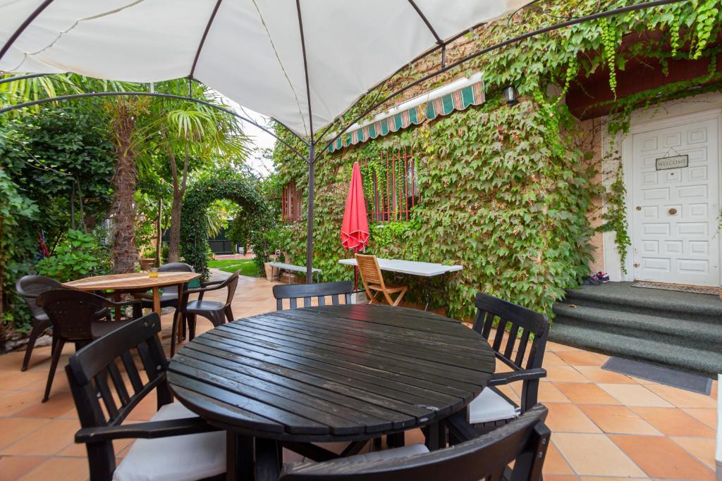 a patio with a table and chairs and a green wall at Paraiso Rooms Coliving in Madrid