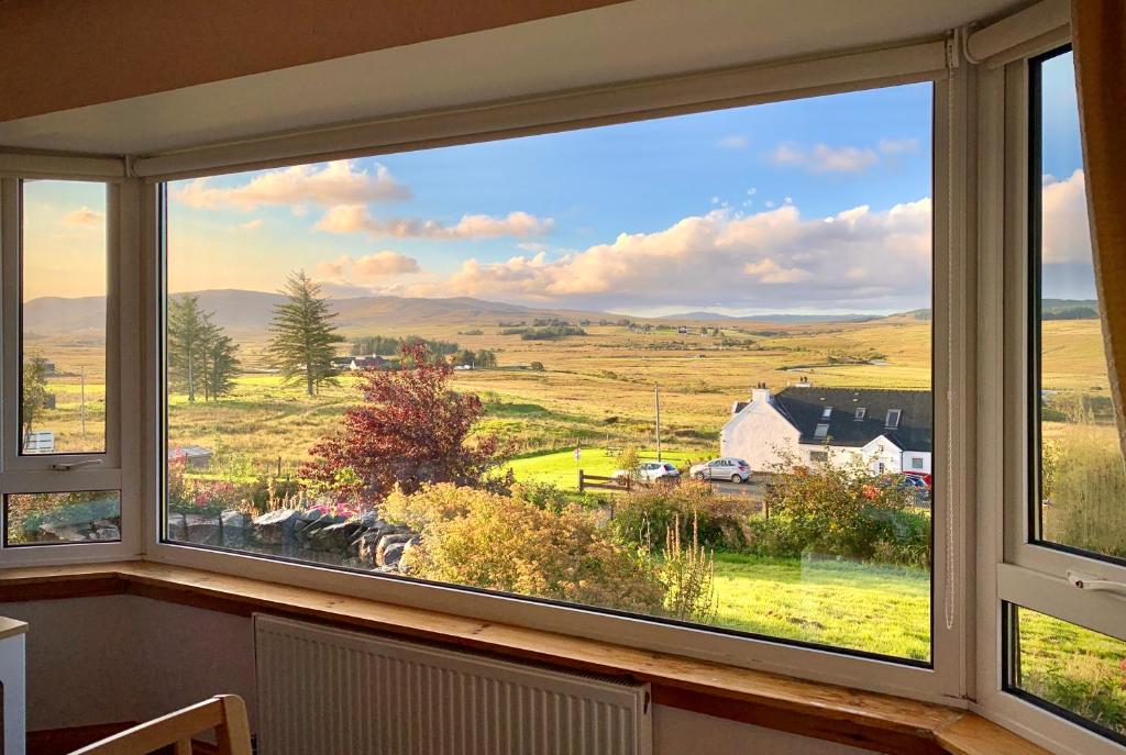 una ventana con vistas a un campo y una casa en Blacksmith holiday cottage near Portree in central Skye en Portree