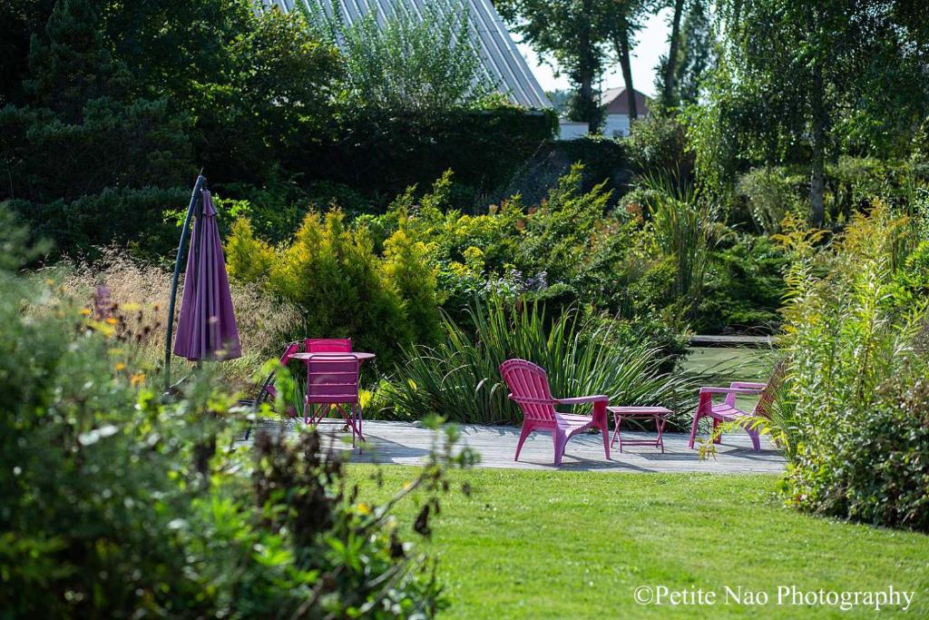 uma mesa e cadeiras e um guarda-sol num jardim em Au Jardin des Deux Ponts em Abbeville