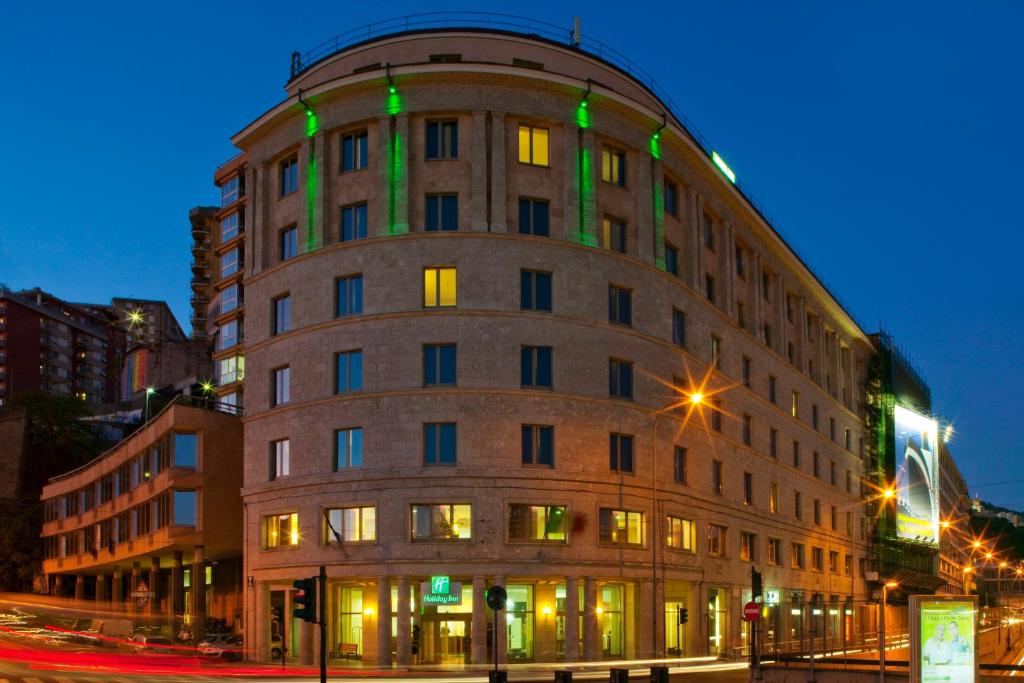 ジェノヴァにあるホリデー イン ジェノア シティの緑色の灯りが灯る建物