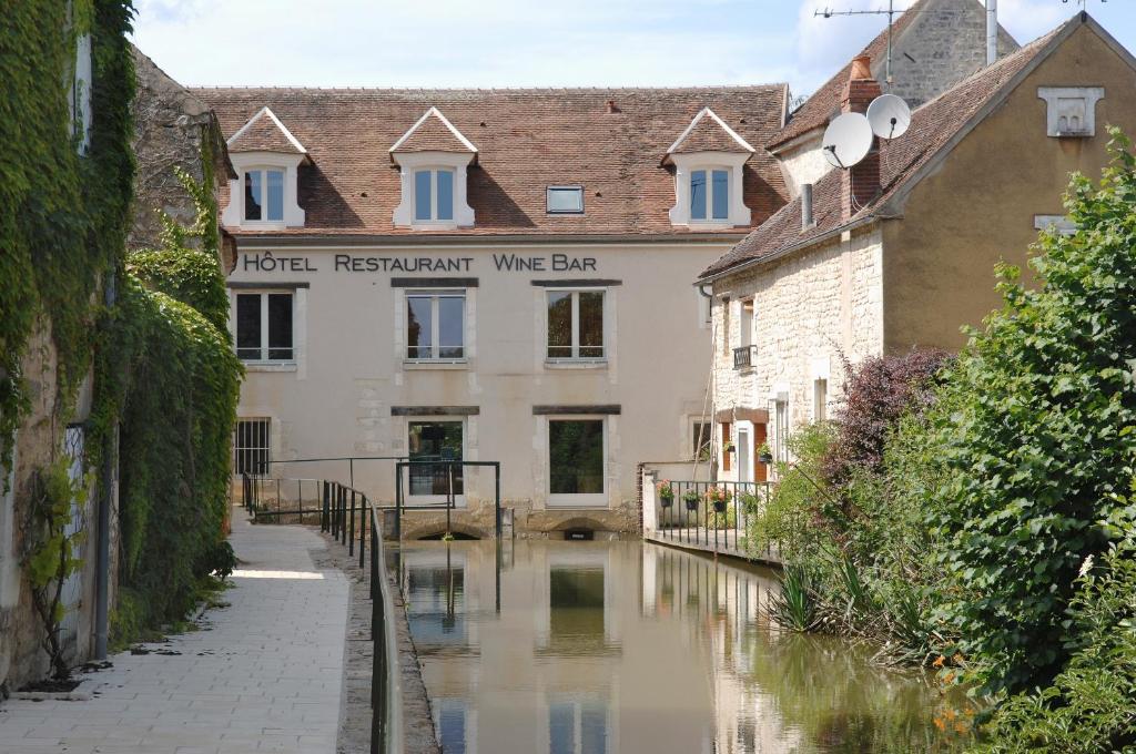 um canal no meio de uma cidade com um edifício em Au Vieux Moulin em Chablis