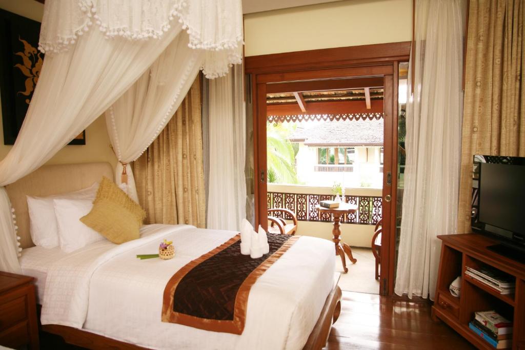 a bedroom with a bed and a tv and a window at Khum Phaya Resort & Spa Boutique Collection in Chiang Mai