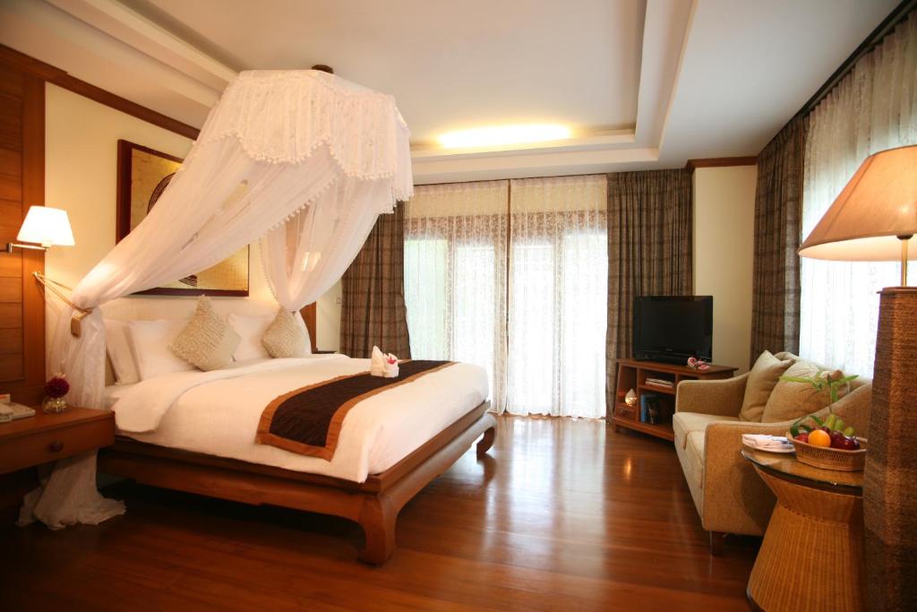 a hotel room with a bed and a couch at Khum Phaya Resort & Spa Boutique Collection in Chiang Mai