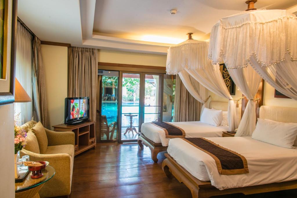a hotel room with two beds and a television at Khum Phaya Resort & Spa Boutique Collection in Chiang Mai