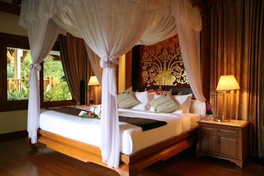 a bedroom with a bed with a canopy at Khum Phaya Resort & Spa Boutique Collection in Chiang Mai