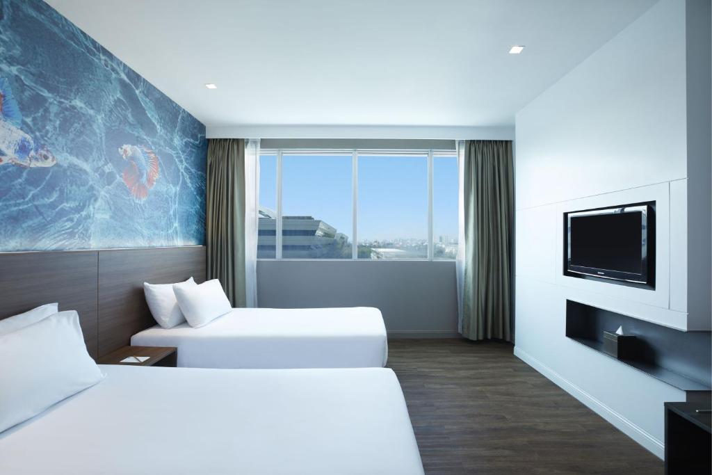 a hotel room with two beds and a flat screen tv at Centara Life Government Complex Hotel & Convention Centre Chaeng Watthana in Bangkok