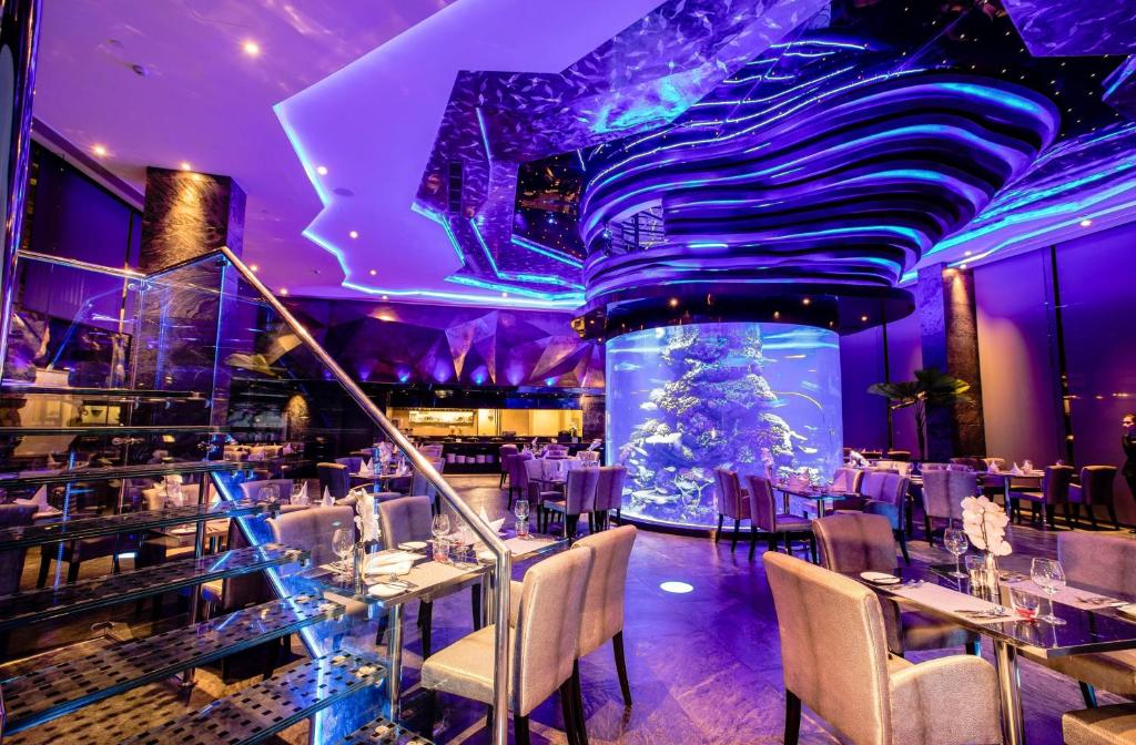 un ristorante con illuminazione viola, tavoli e sedie di Centara Azure Hotel Pattaya a Centro di Pattaya