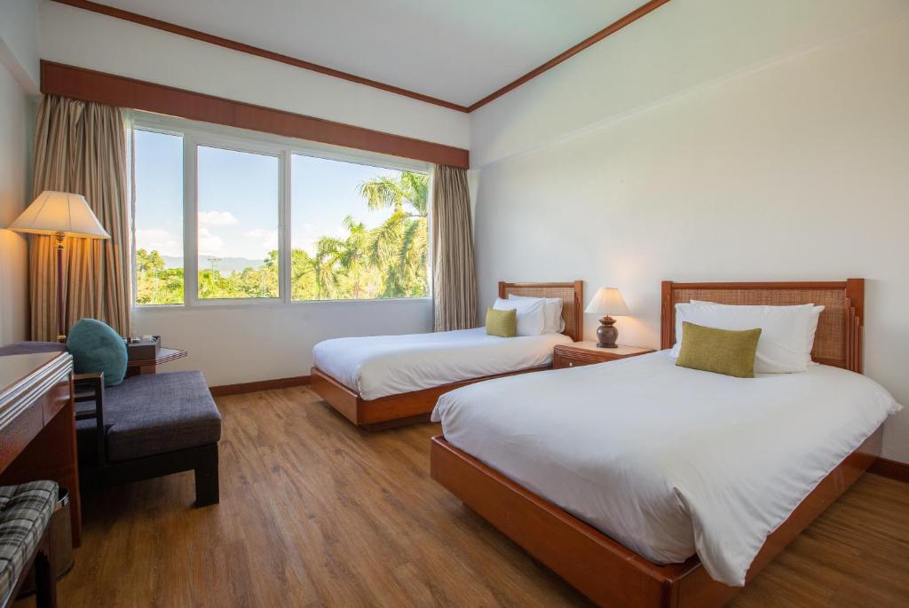 a hotel room with two beds and a window at Centara Life Hotel Mae Sot in Mae Sot