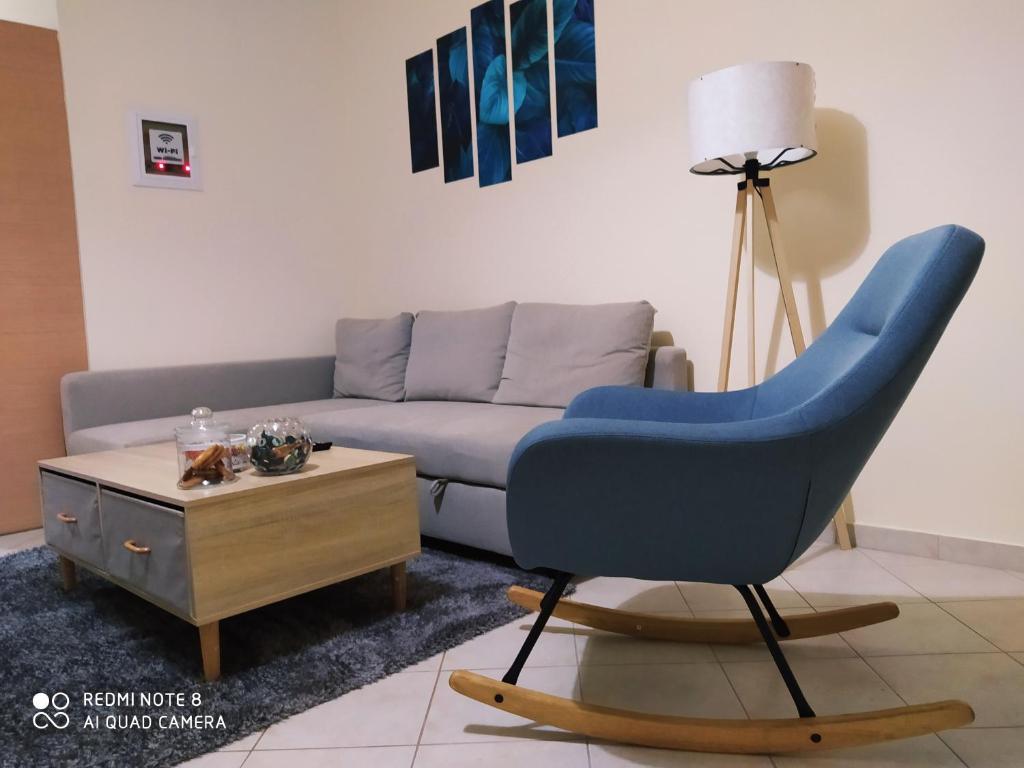 a living room with a blue chair and a couch at Agis Residence in Agios Rokkos