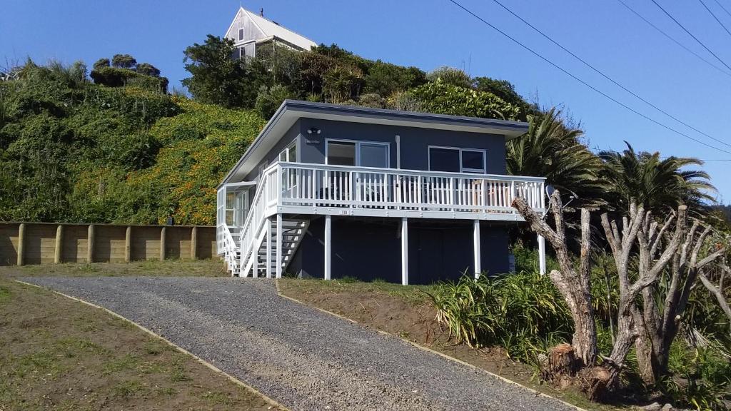 een huis aan de zijkant van een heuvel met een oprit bij Karoro the beach front bach with views to die for! in Raglan