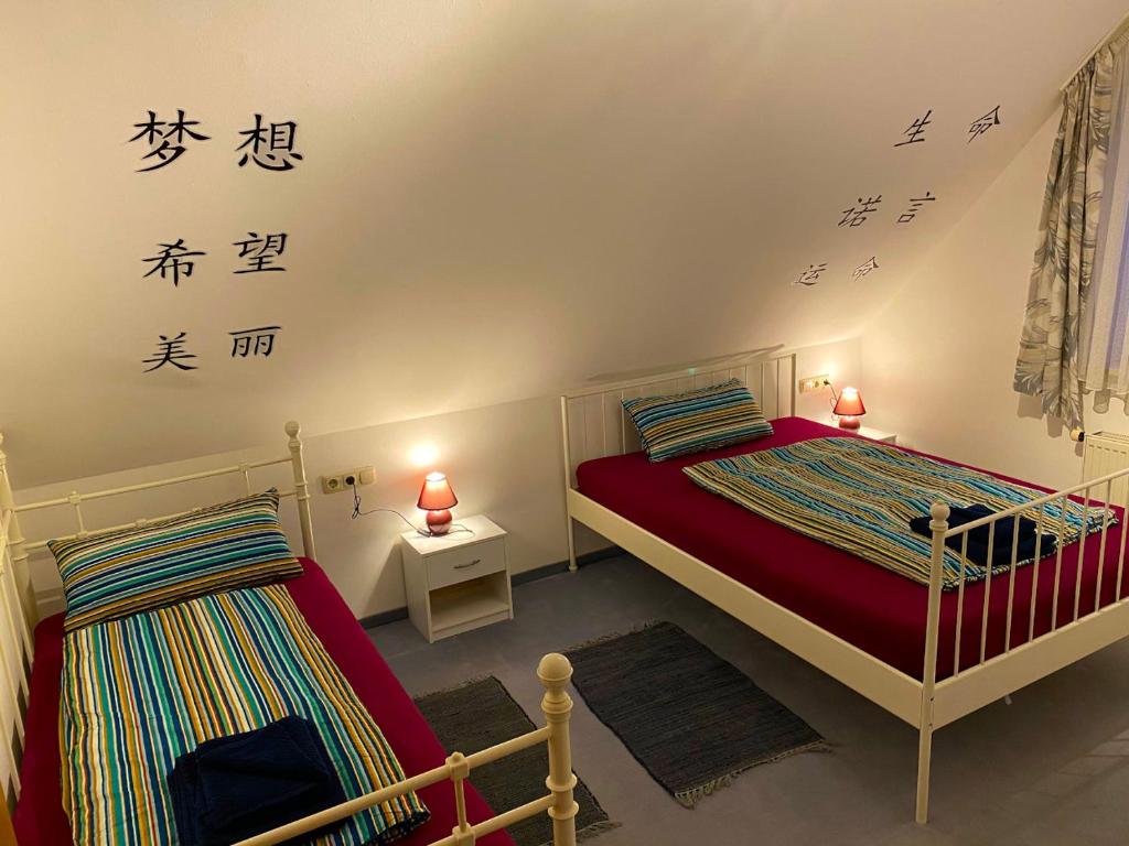 2 camas en una habitación con escritura asiática en la pared en Ferienwohnung Dinkelscherben, en Dinkelscherben