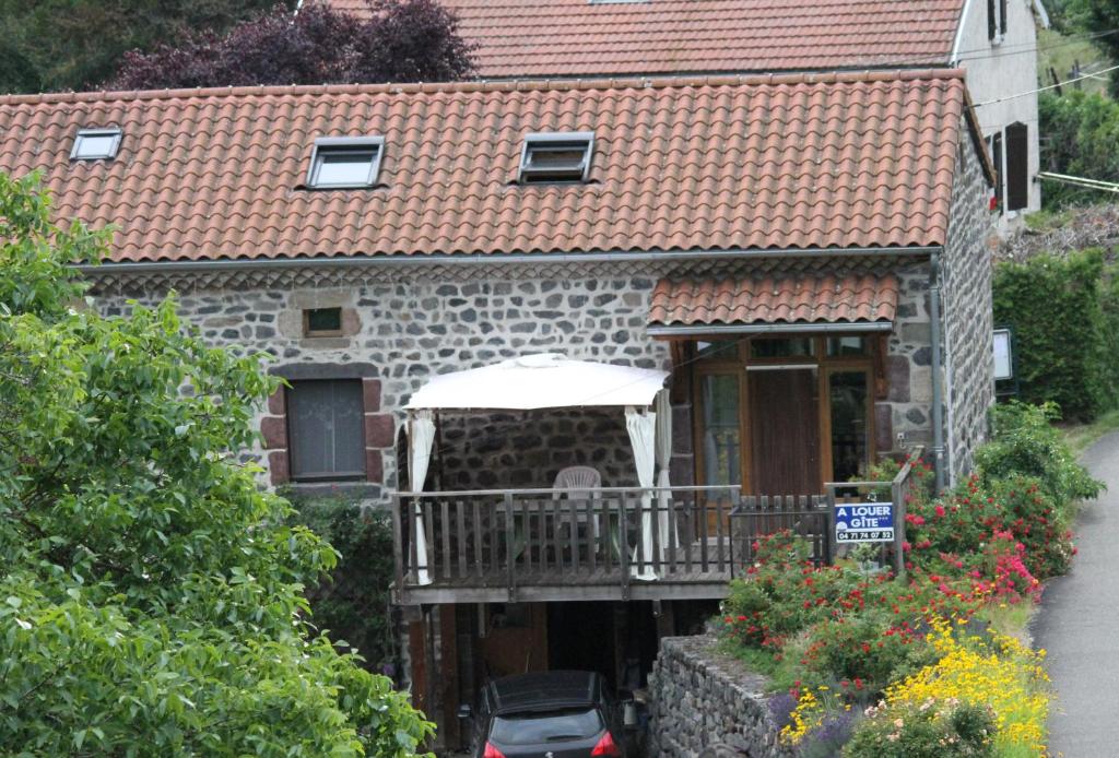 a stone house with a porch and a balcony at gîte de Véreuges in Saint-Julien-des-Chazes