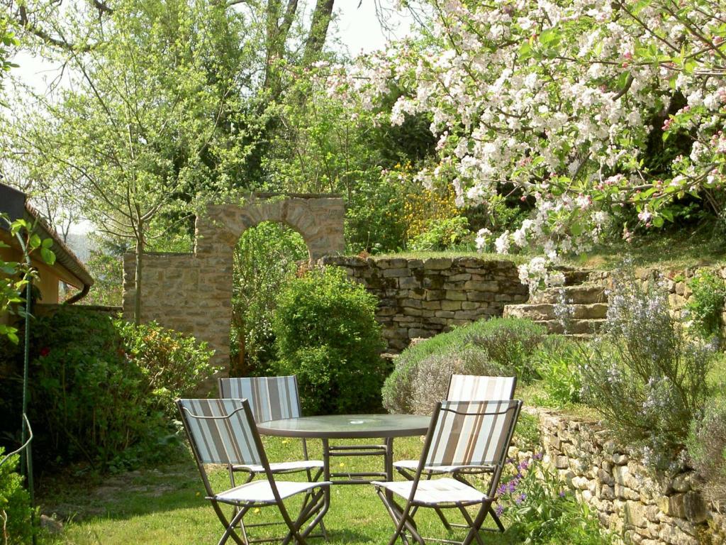 einen Tisch und Stühle in einem Garten mit Blumen in der Unterkunft Le Verger Sous Les Vignes in Villeferry