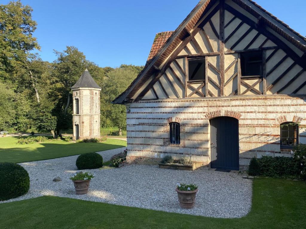 ein Steingebäude mit einem Uhrturm im Hof in der Unterkunft Charming half-timbered house on quiet waterside between Abbeville and Amiens in Fransu
