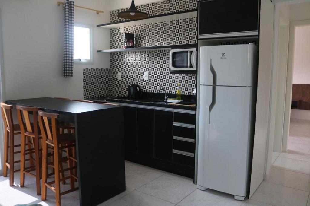 uma cozinha com um frigorífico branco e uma bancada preta em Nosso Cantinho Canasvieiras em Florianópolis