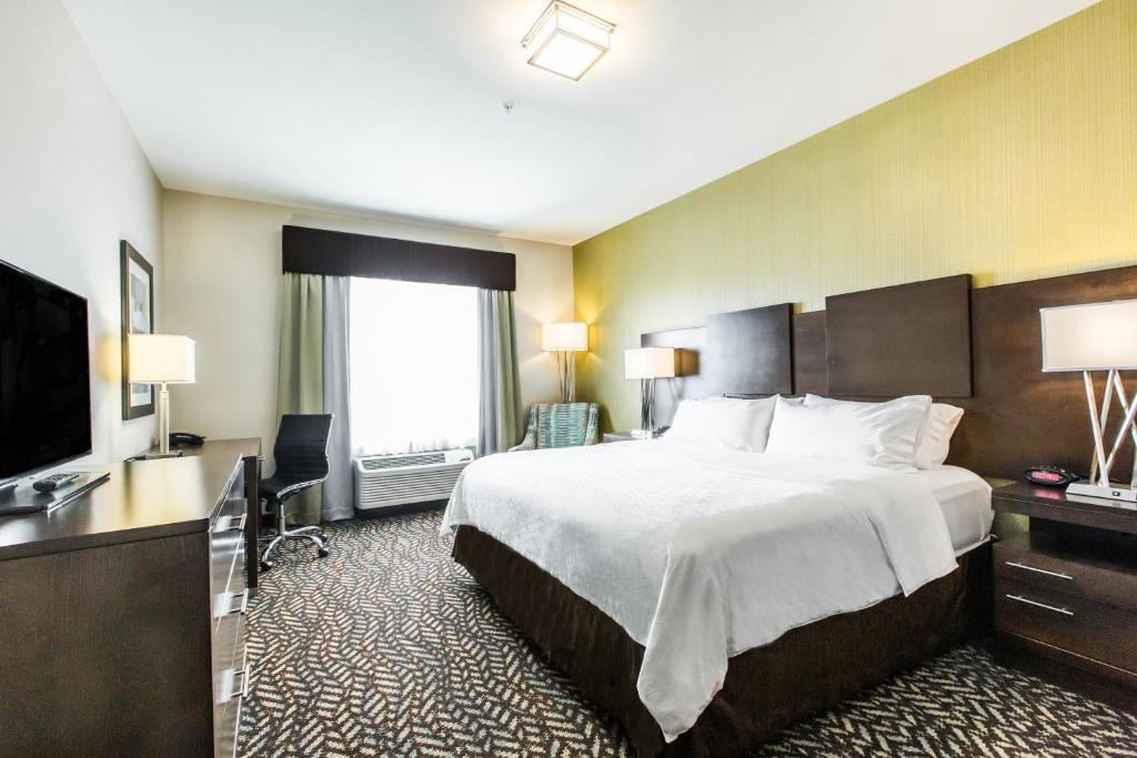 a hotel room with a large bed and a flat screen tv at Holiday Inn Express & Suites Spruce Grove - Stony Plain by IHG in Spruce Grove