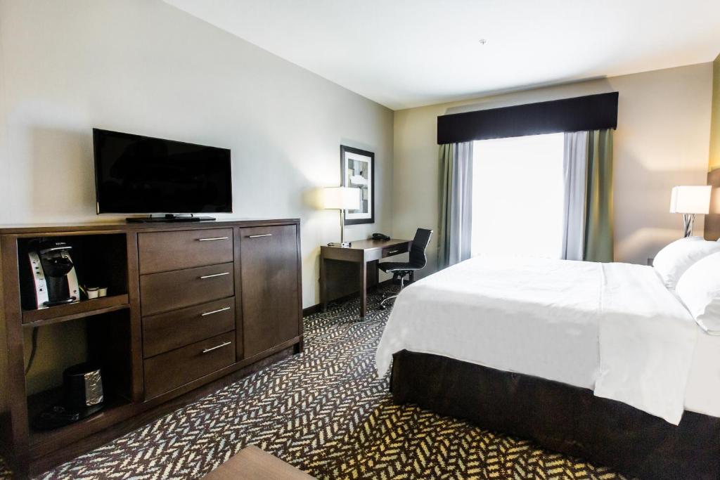 a hotel room with a bed and a flat screen tv at Holiday Inn Express & Suites Spruce Grove - Stony Plain by IHG in Spruce Grove