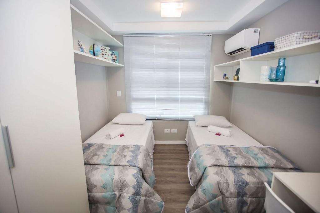 two beds in a small room with a window at Studio com 2 Camas de Solteiro - ALL0703 in Curitiba