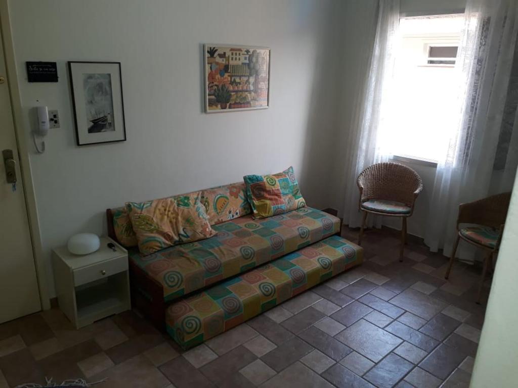- un salon avec un canapé et une fenêtre dans l'établissement Apartamento na enseada 50 metros da praia, à Guarujá