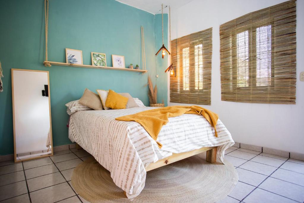 1 dormitorio con cama y pared azul en “Casa Raíz” habitaciones Boho, en Tequila