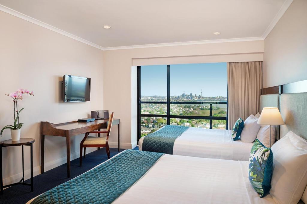 a hotel room with two beds and a desk and a window at The Spencer Hotel in Auckland