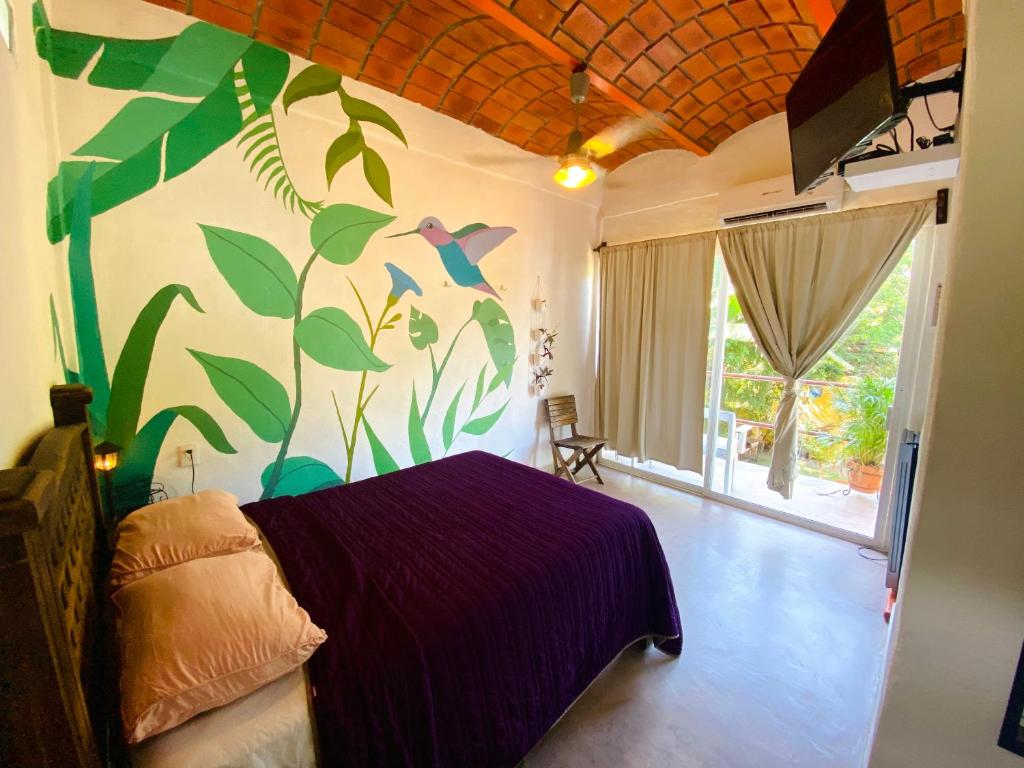a bedroom with a purple bed with a mural on the wall at Habitacion privada con pisicina y cocina compartida in Sayulita