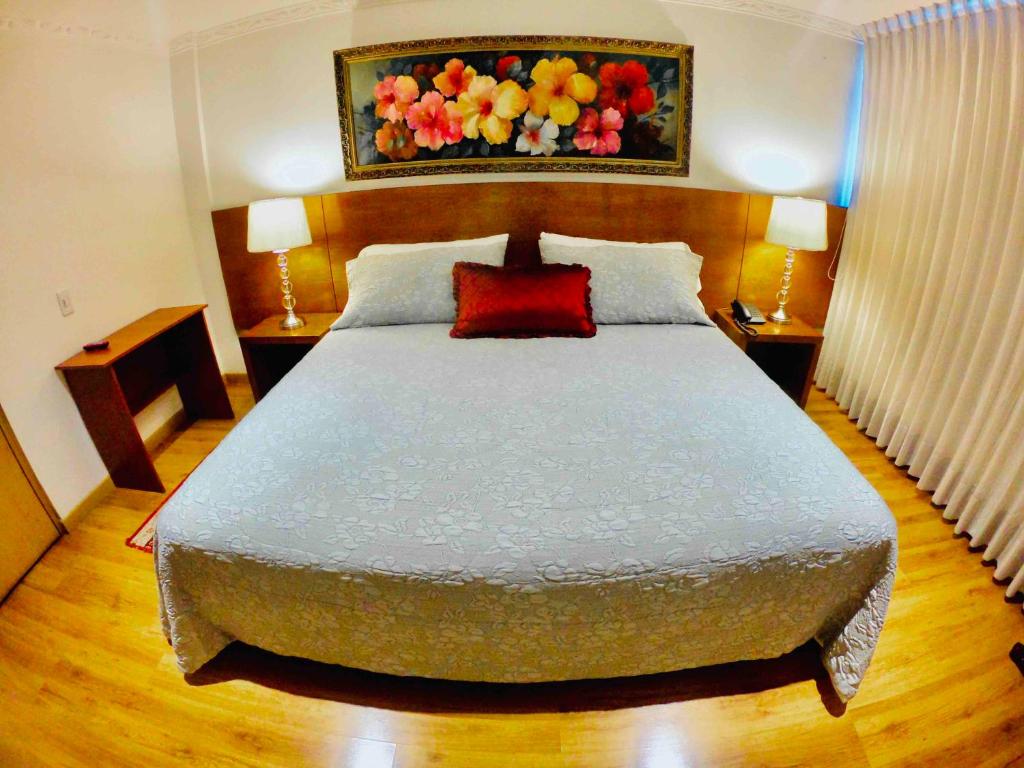 a bedroom with a large bed with a red pillow at Hotel Casa Mahanaim Colferias, Bogotá in Bogotá