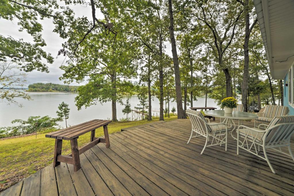 una terraza de madera con mesa, sillas y banco en Kentucky Lake Cabin with Private Dock and Fire Pit, en New Concord