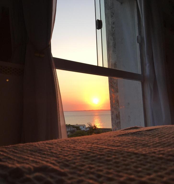 a view of a sunset from a bedroom window at Encantos no Porto da Barra in Salvador